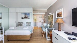 A modern bedroom with a bed, desk, and TV. - First Beach 203 by Ctha (Cape Town)
