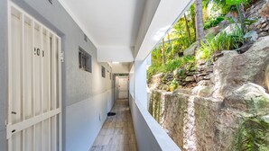 A narrow corridor with a stone wall on one side and a door on the other. - First Beach 203 by Ctha (Cape Town)