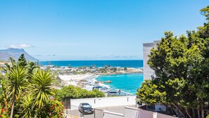 A coastal view with a beach, cars, and a building. - First Beach 203 by Ctha (Cape Town)