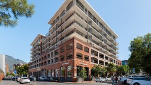 A multi-story building with a prominent SOFI company sign, multiple balconies, and a parking area with cars. - Rockwell 221 by Ctha (Cape Town)