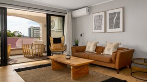 A modern living room with a wooden coffee table, a brown leather sofa, and a wicker chair. - Rockwell 221 by Ctha (Cape Town)