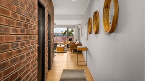 A modern interior with a brick wall, wooden flooring, and a seating area with a sofa and chairs. - Rockwell 221 by Ctha (Cape Town)