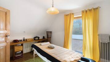 Ein Zimmer mit Bett, Schreibtisch, Stuhl, Heizkörper und einem fensterbepflanzten Fenster.