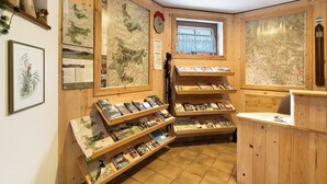 Interior em madeira com mapas, um relógio e uma janela.
