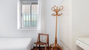A room with a bed, a window with a view, a coat rack, and a wardrobe.