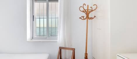 A room with a bed, a window with a view, a coat rack, and a wardrobe.
