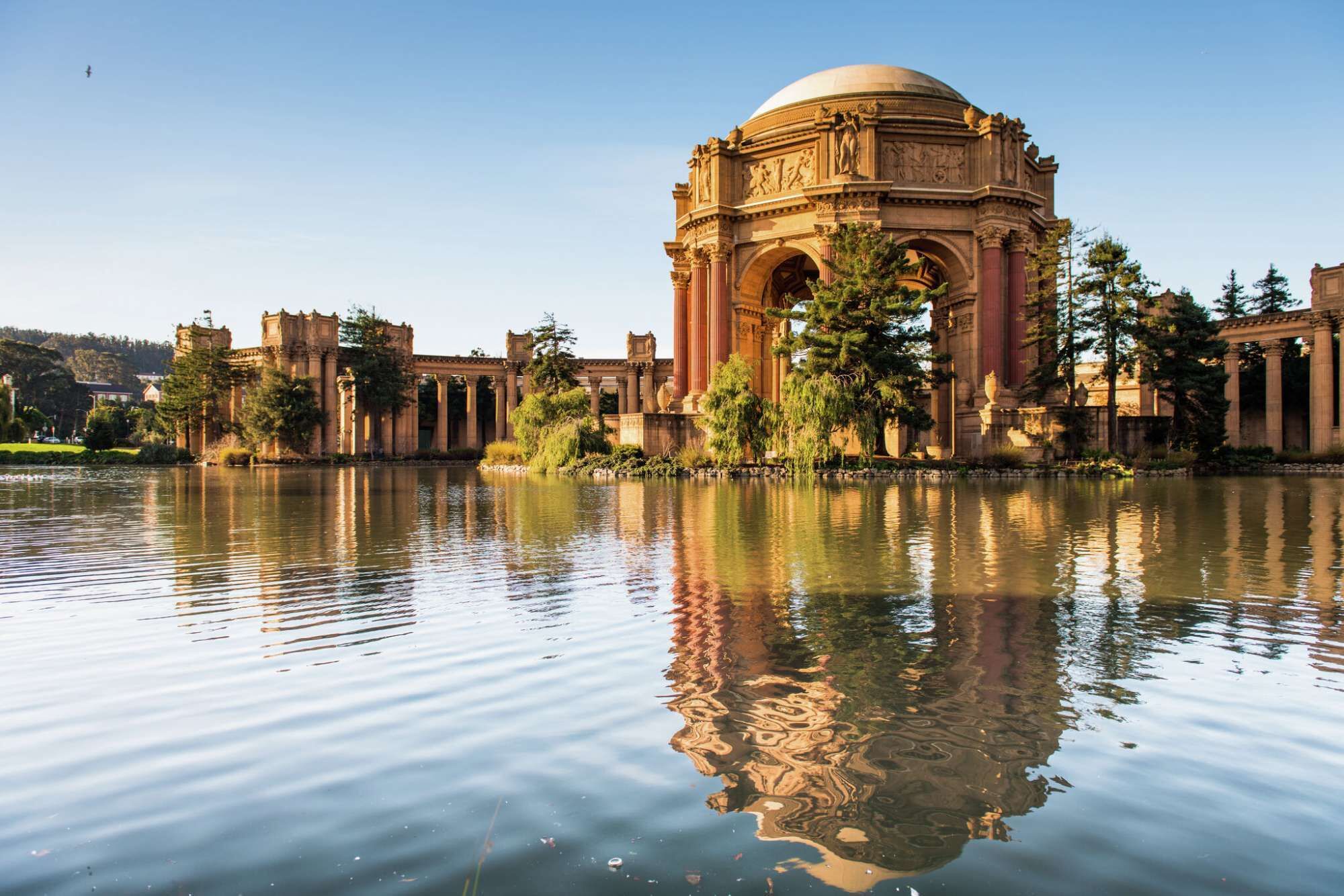 Un edifici històric amb una cúpula gran i columnes clàssiques, reflectint en una calma massa d'aigua.