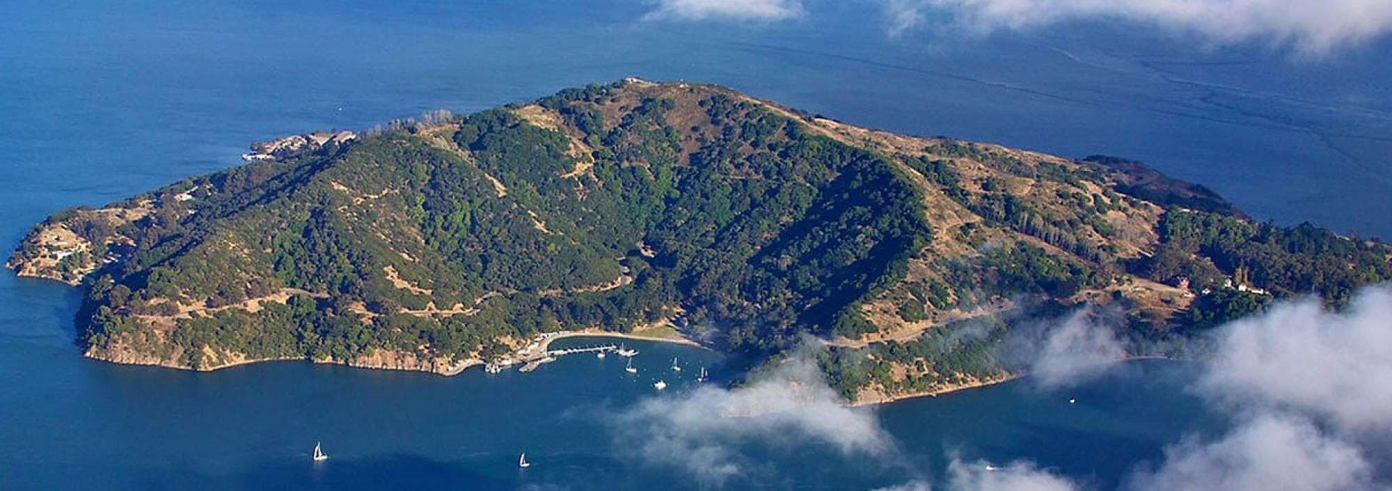 Eine Luftaufnahme einer gebirgigen Insel mit einem kleinen Hafen und Booten.