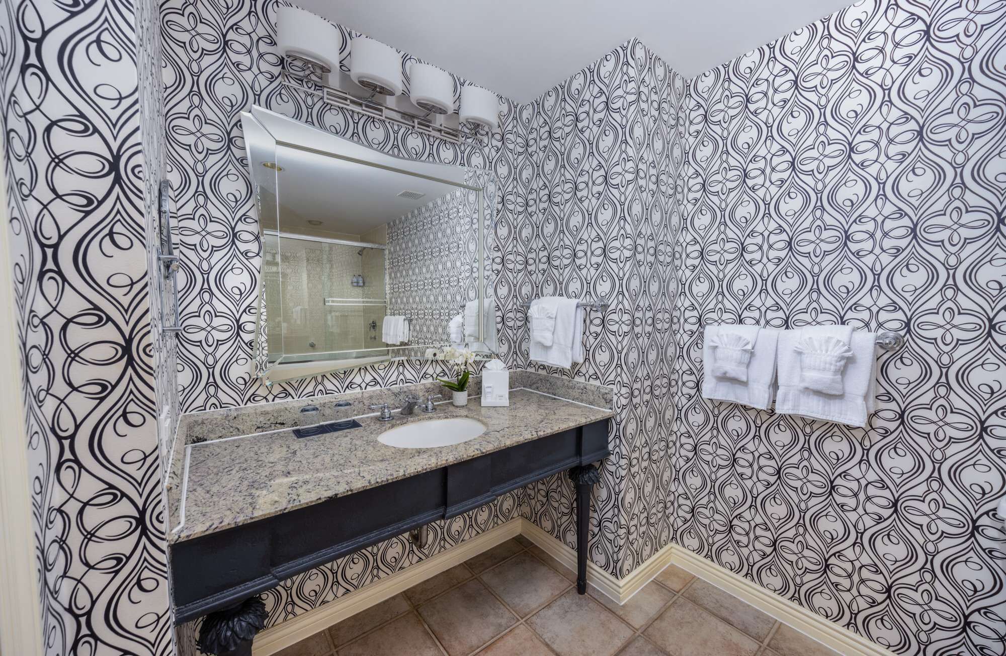 Un baño con lavamanos, espejo y toallero.