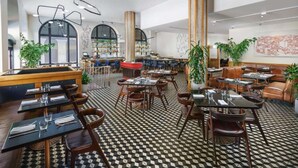 A spacious restaurant with high ceilings, black and white checkered flooring, and a variety of seating arrangements including booths and tables. - Union Square Stay | Bar. Restaurant + Gym (San Francisco)