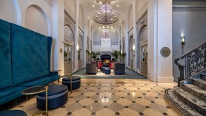 A grand lobby with a checkered floor, a blue sofa, and a chandelier. - Union Square Stay | Bar. Restaurant + Gym (San Francisco)