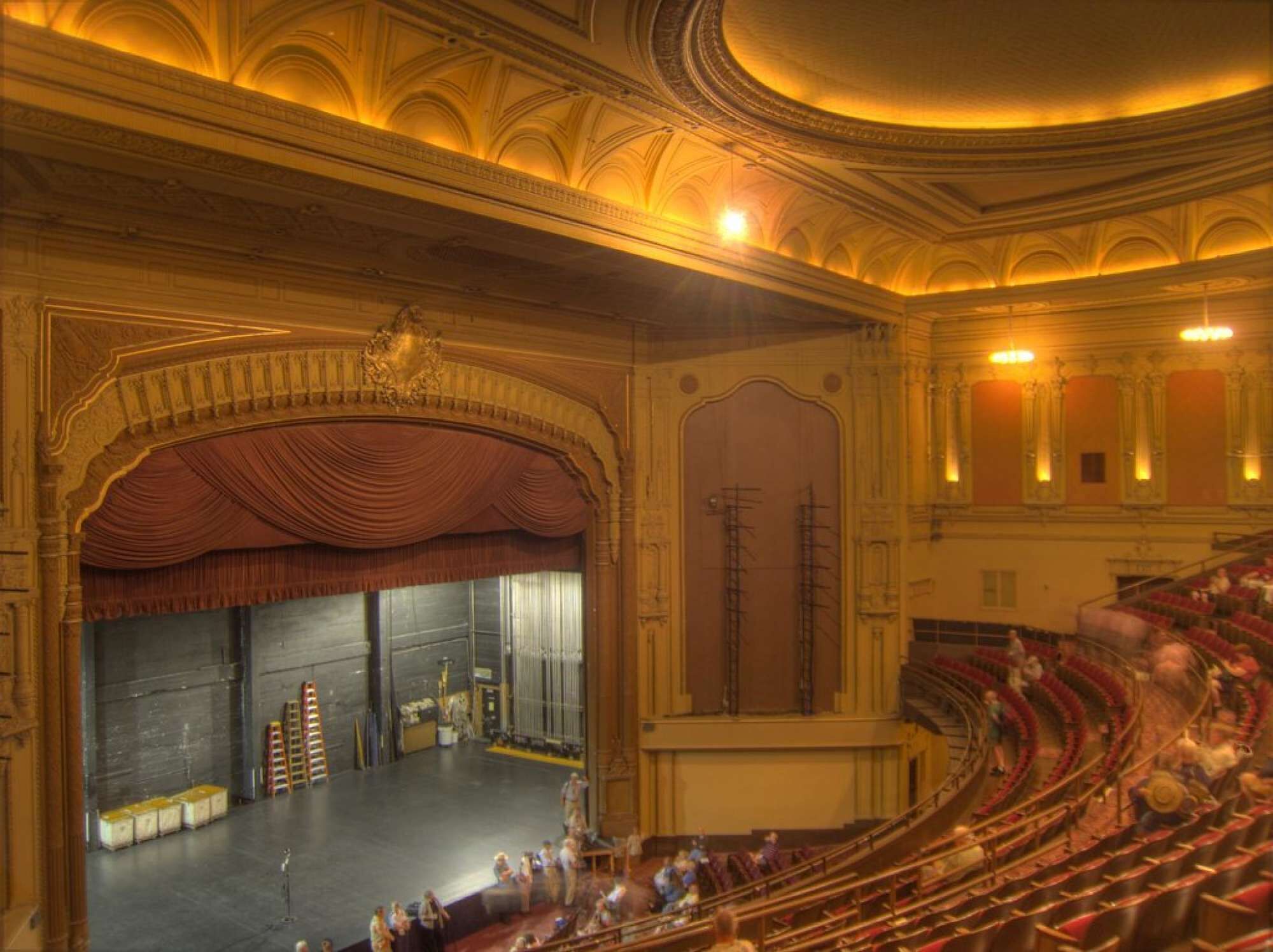 An indoor theater with ornate architecture, a stage, and tiered seating.