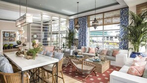 A spacious living area with a large dining table, comfortable seating, and a view of the outdoors. - Steps to Miami Beach + On-site Dining. Pool. Bikes (Miami Beach)