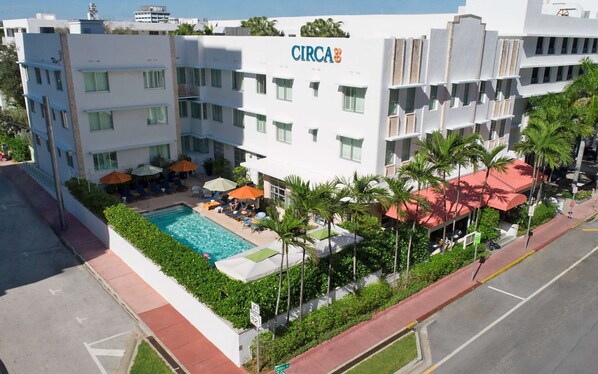 A hotel with a pool, outdoor seating, and palm trees. - Miami Beach Access + On-site Dining. Pool. Bikes. (Miami Beach)