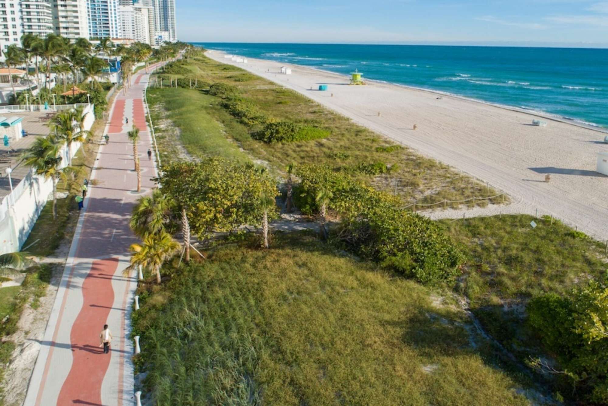 A coastal road with a red path, beach, and ocean.