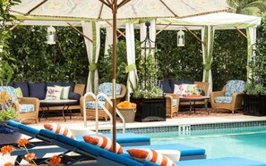 A poolside area with lounge chairs, a covered seating area, and a pool. - Miami Beach Access + On-site Dining. Pool. Bikes. (Miami Beach)
