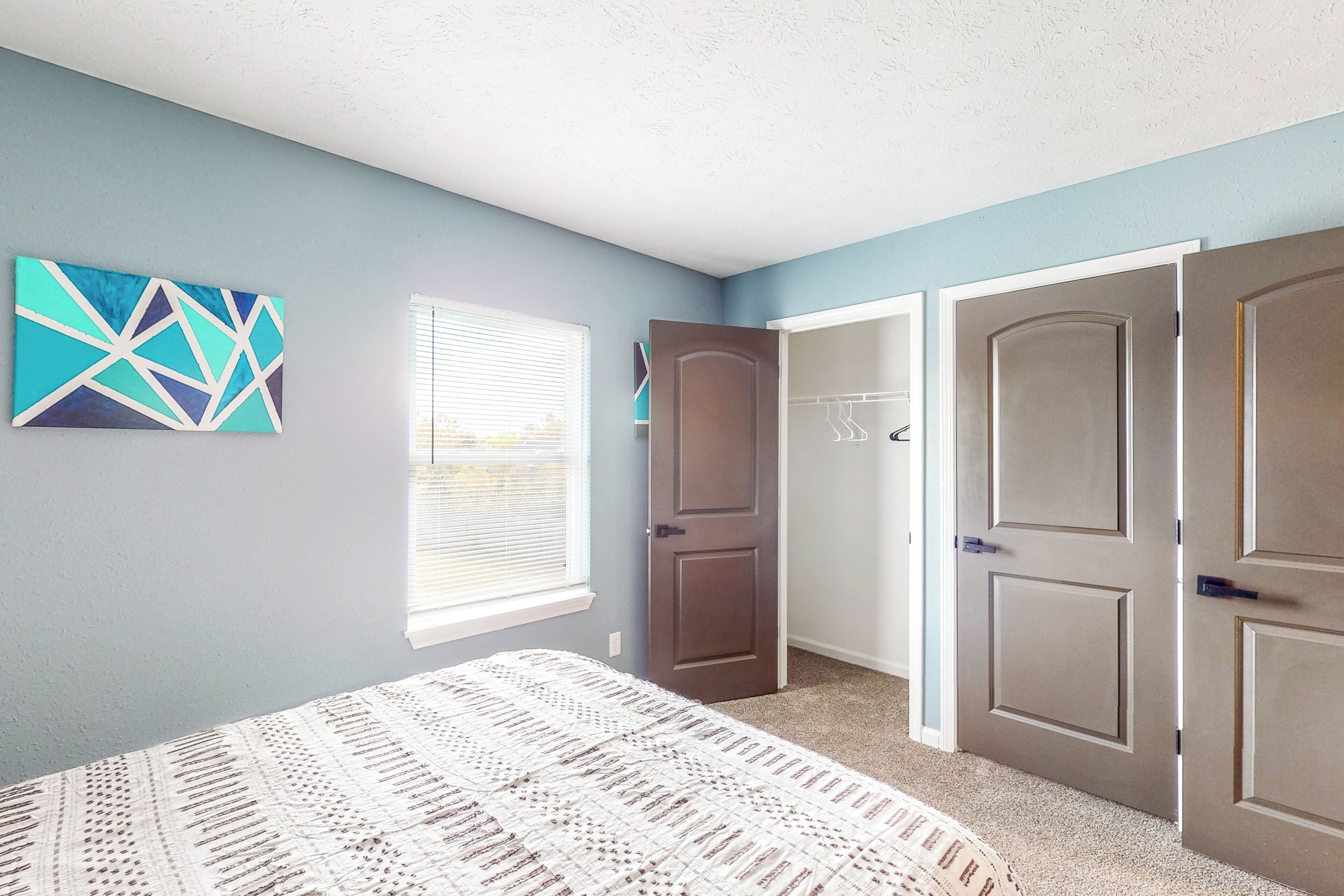 A bedroom with a bed, a door, and a window.