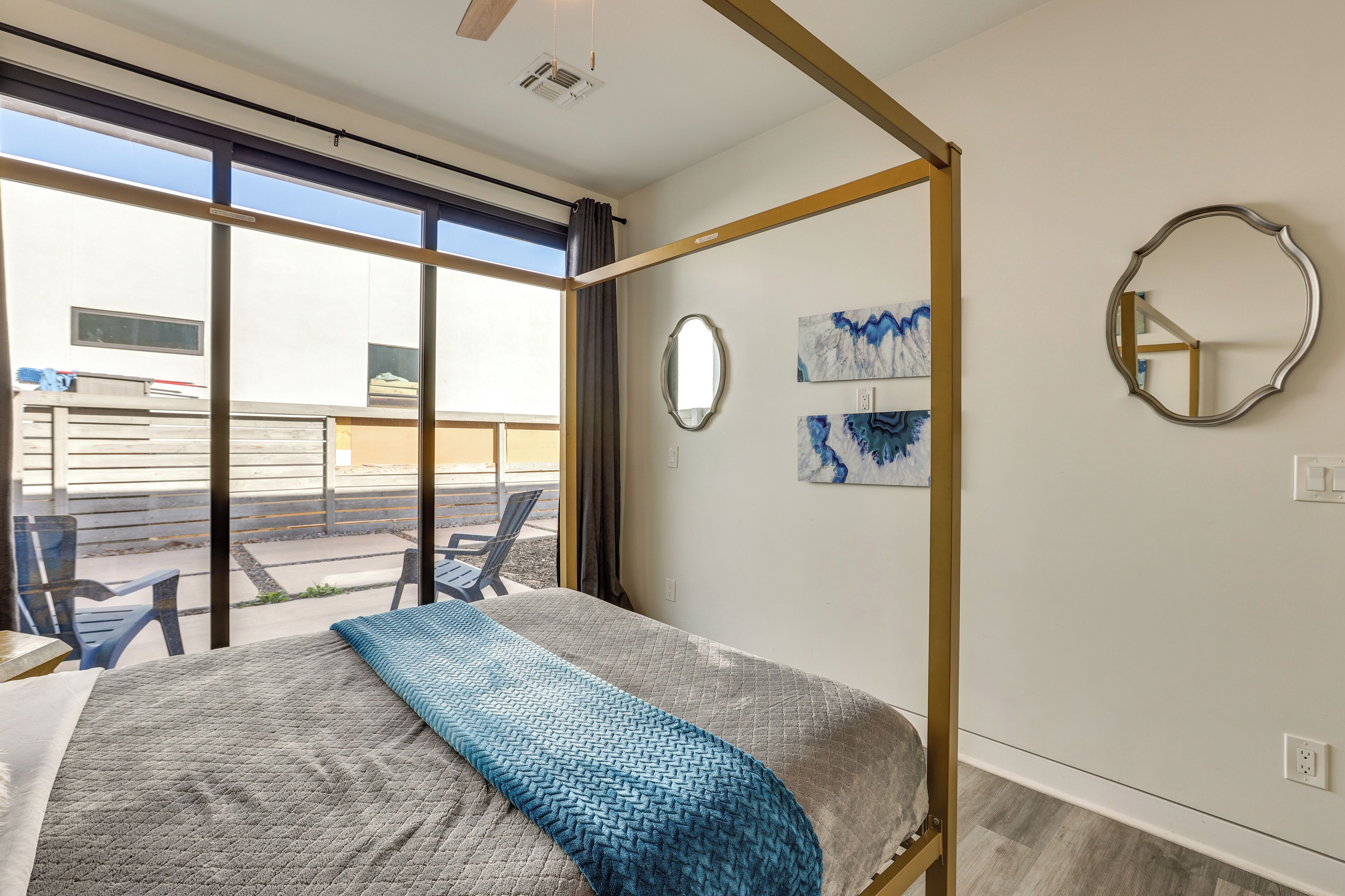 A modern bedroom with a large bed, a balcony with chairs, and artwork on the walls.