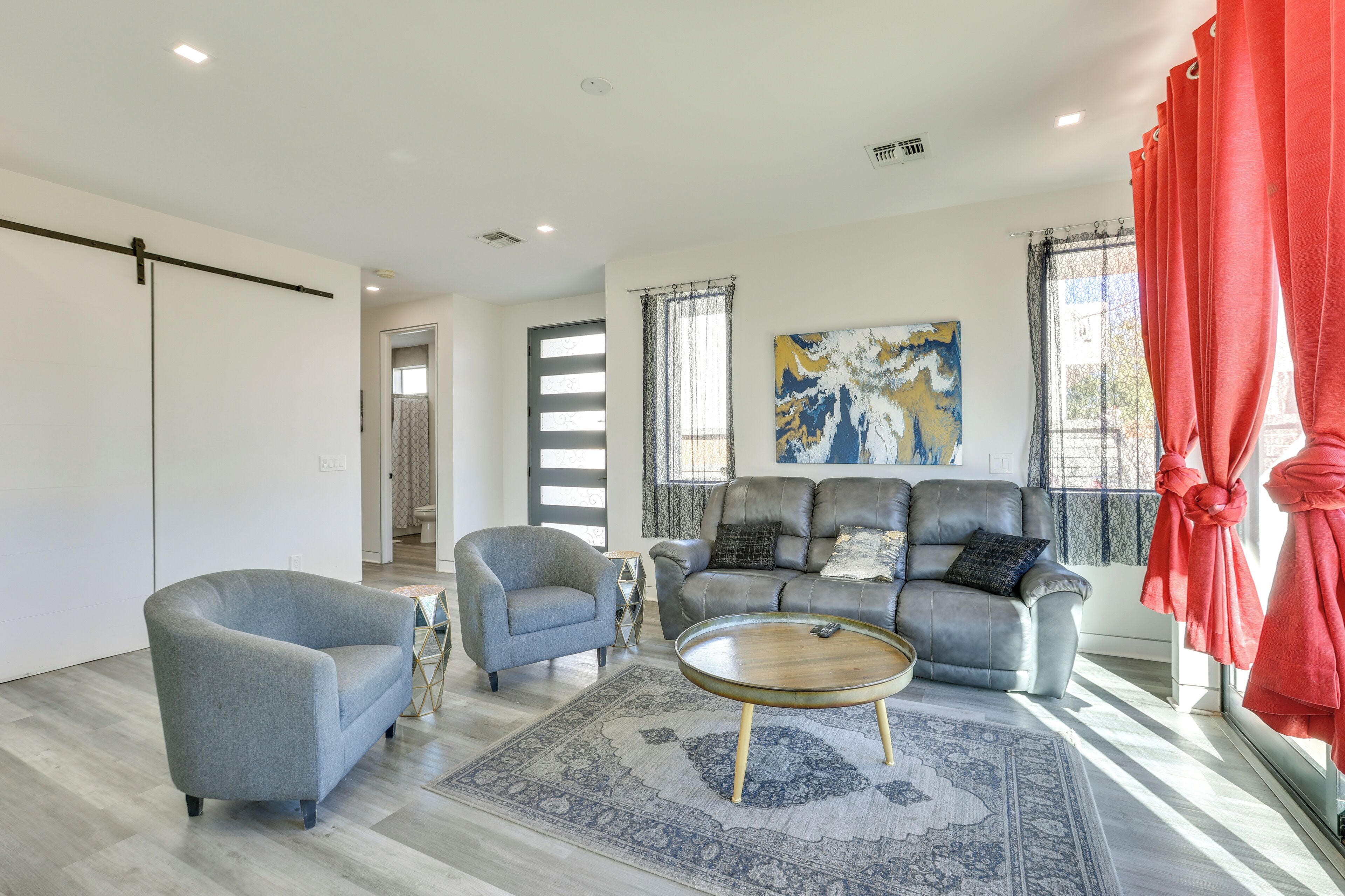 A modern living room with a grey sofa, a grey armchair, and a round coffee table.