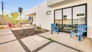 Une terrasse avec des sièges extérieurs, un bâtiment moderne et un ciel dégagé.