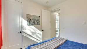 Une chambre à coucher avec un lit, une porte, une œuvre d’art accrochée au mur et un miroir.