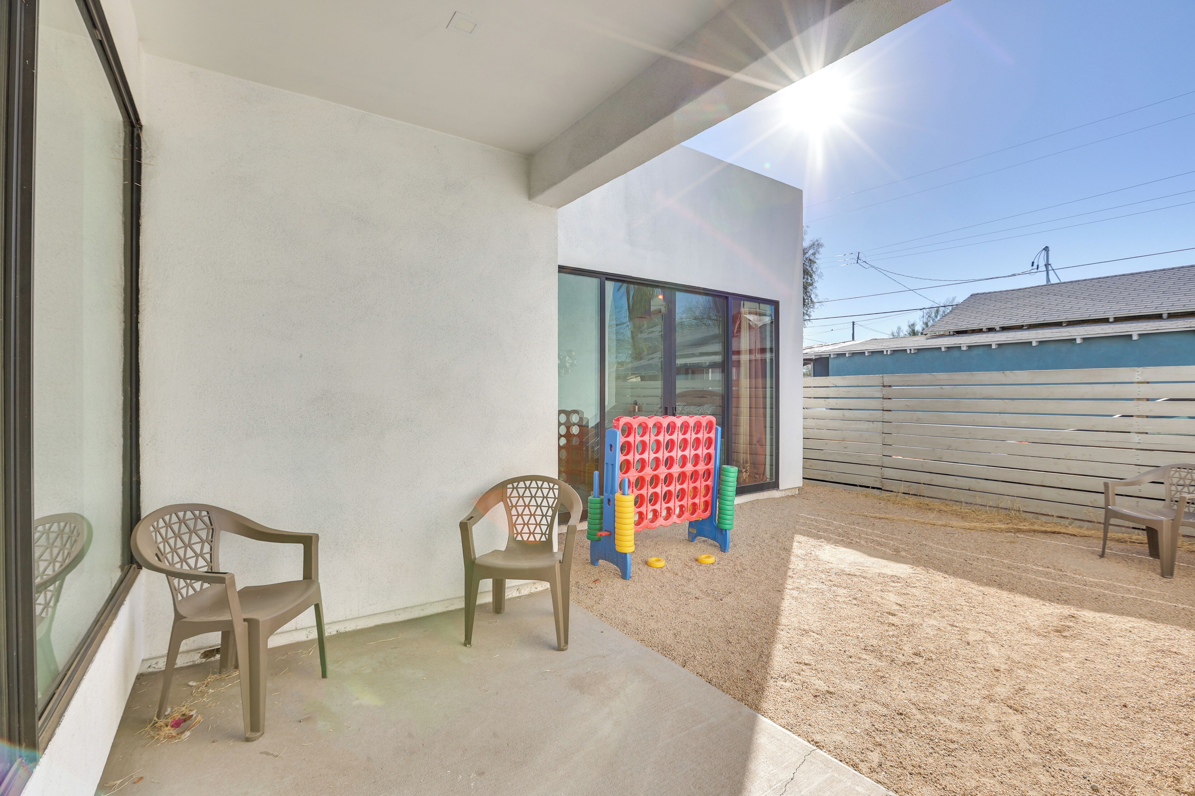 A modern building exterior with a glass door, two plastic chairs, and a colorful play structure.