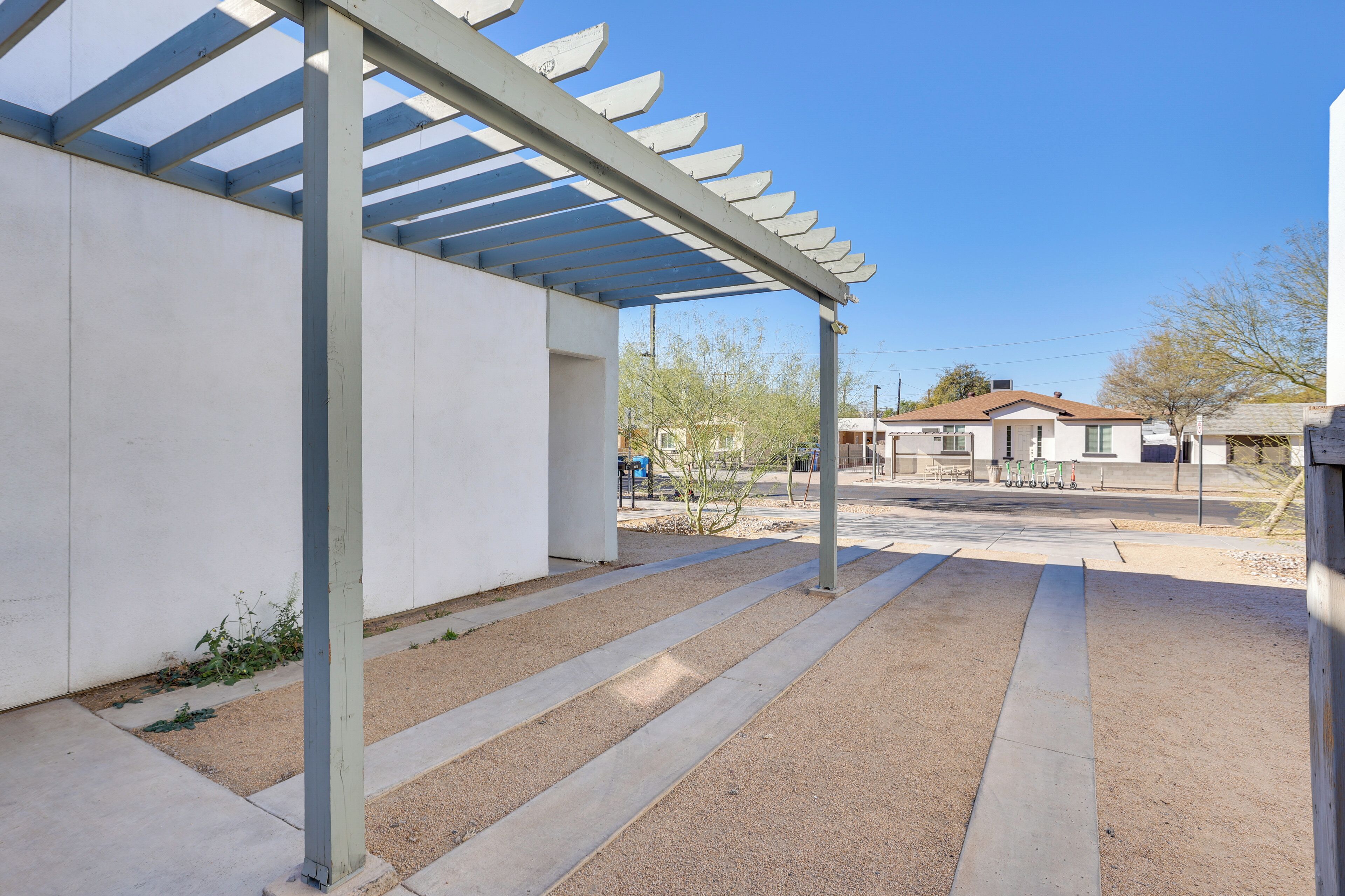 Un espacio al aire libre techado, con suelo de concreto y vigas de metal.