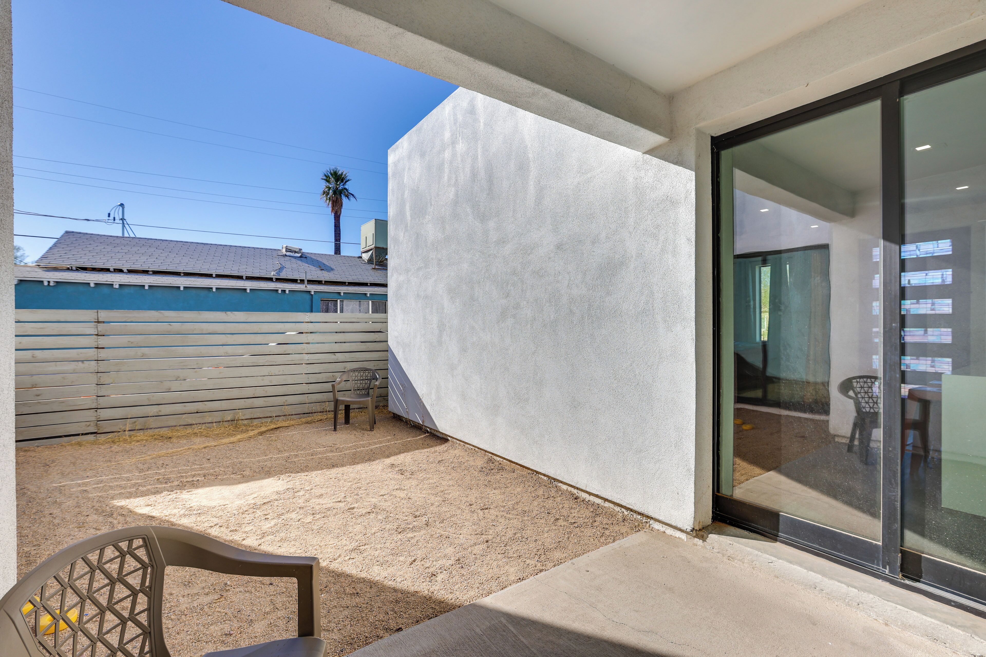 A modern building with a concrete exterior, a glass door, and a patio area with a chair and a table.
