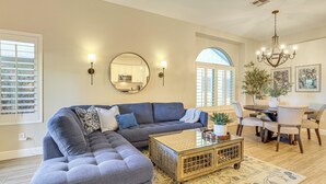 Ein Wohnzimmer mit einem Ecksofa, einem Couchtisch und einem Essbereich mit Stühlen und Tisch.