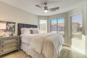 A bedroom with a bed, a dresser, a ceiling fan, and large windows with blinds. - < 1 Mi to Golf: Charming Ahwatukee Foothills Villa (Phoenix)