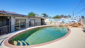 A swimming pool with a brick border, a building with a covered patio, and a mural on the wall. - Private Pool & Patio! Home 8 Mi to Dtwn Phoenix (Phoenix)