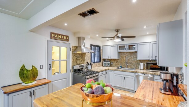 A modern kitchen with white cabinets, a wooden countertop, a stove, and a ceiling fan. - Private Pool & Patio! Home 8 Mi to Dtwn Phoenix (Phoenix)