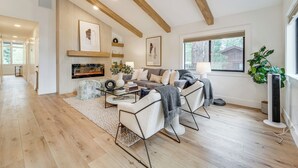 A modern living room with wooden beams, a fireplace, and a large window. - Walk to Gondola: Truckee Retreat w/ Resort Perks! (Truckee)