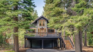 A two-story cabin with a covered garage, surrounded by dense forest. - Walk to Gondola: Truckee Retreat w/ Resort Perks! (Truckee)