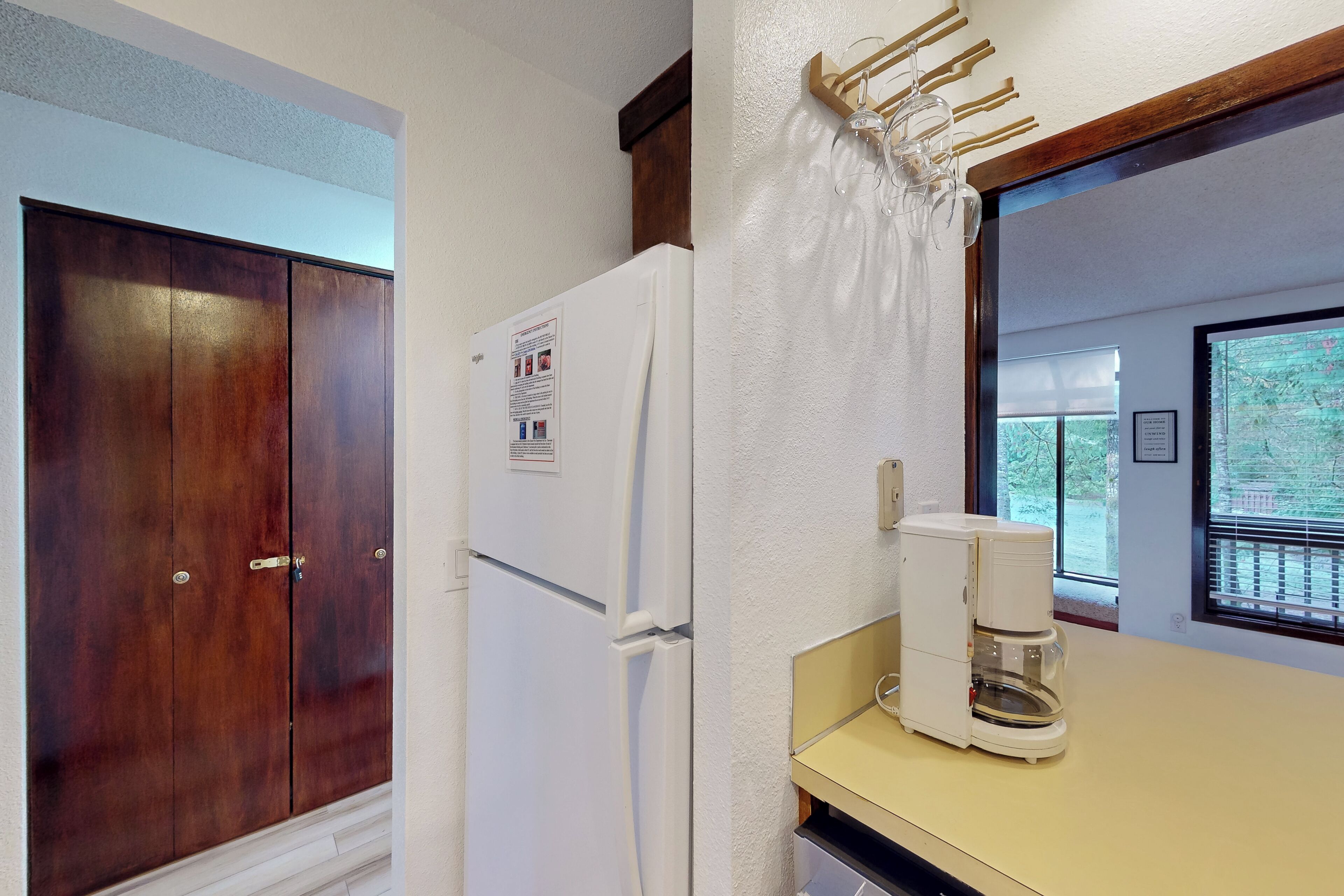 A kitchen with a white refrigerator, a coffee maker, and wooden cabinets.