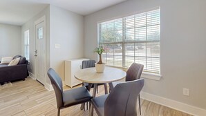 A modern living room with a round table, chairs, a sofa, and a potted plant. - Cozy Duplex Spacious Close to Everything (Pensacola)
