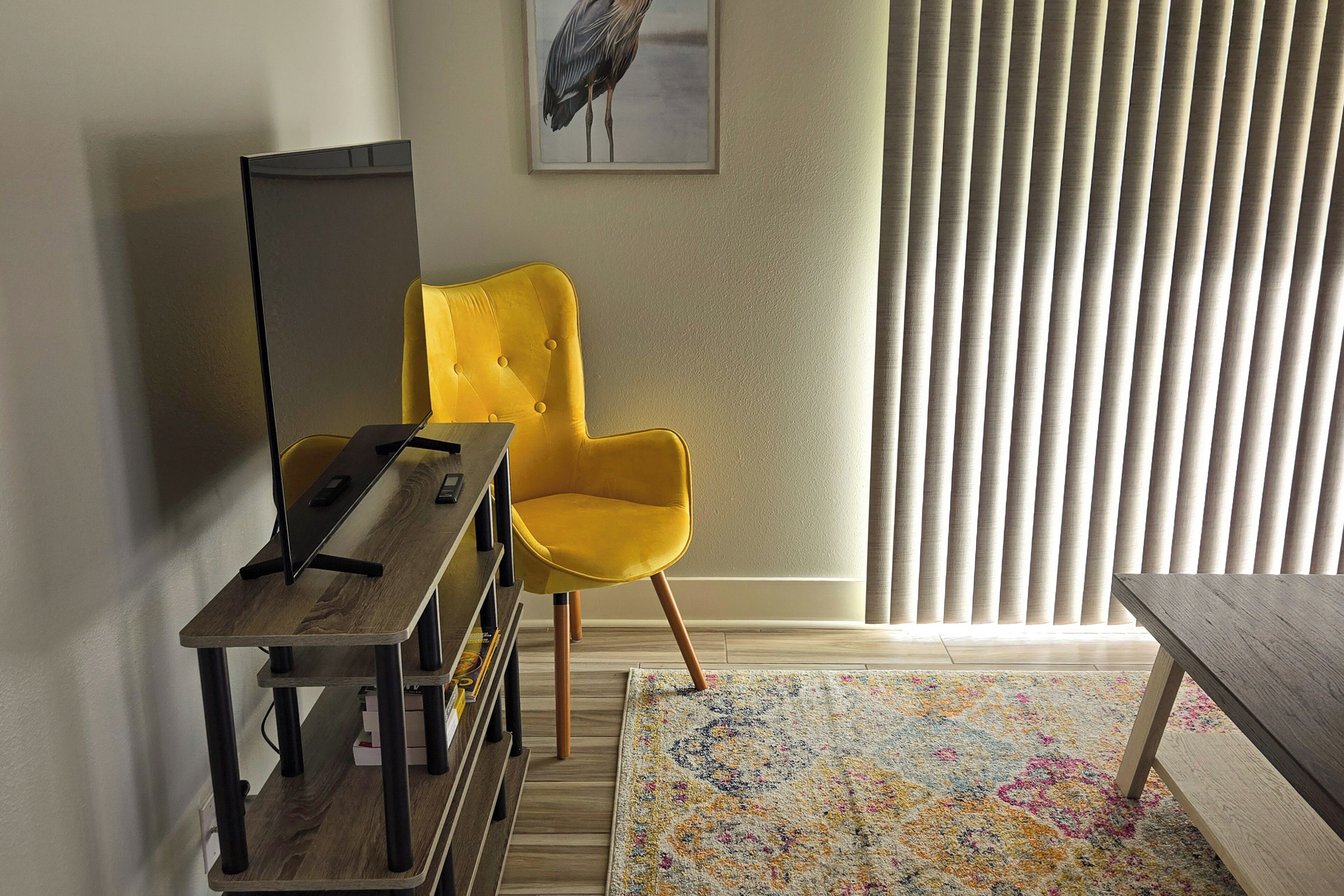 A room with a wooden desk, a yellow chair, a standing lamp, and a patterned rug.