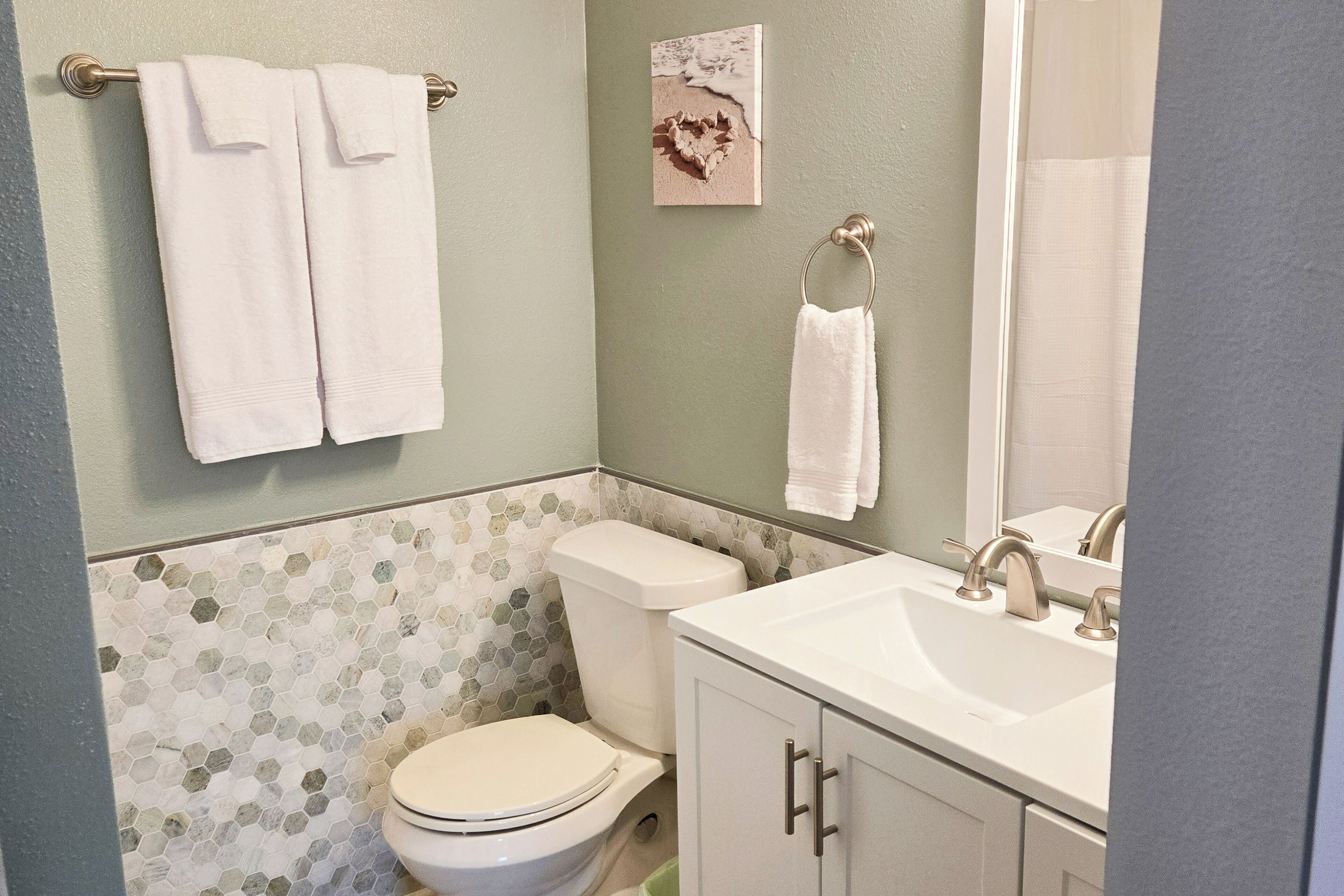 A bathroom with a toilet, sink, and two towels hanging on a towel bar.