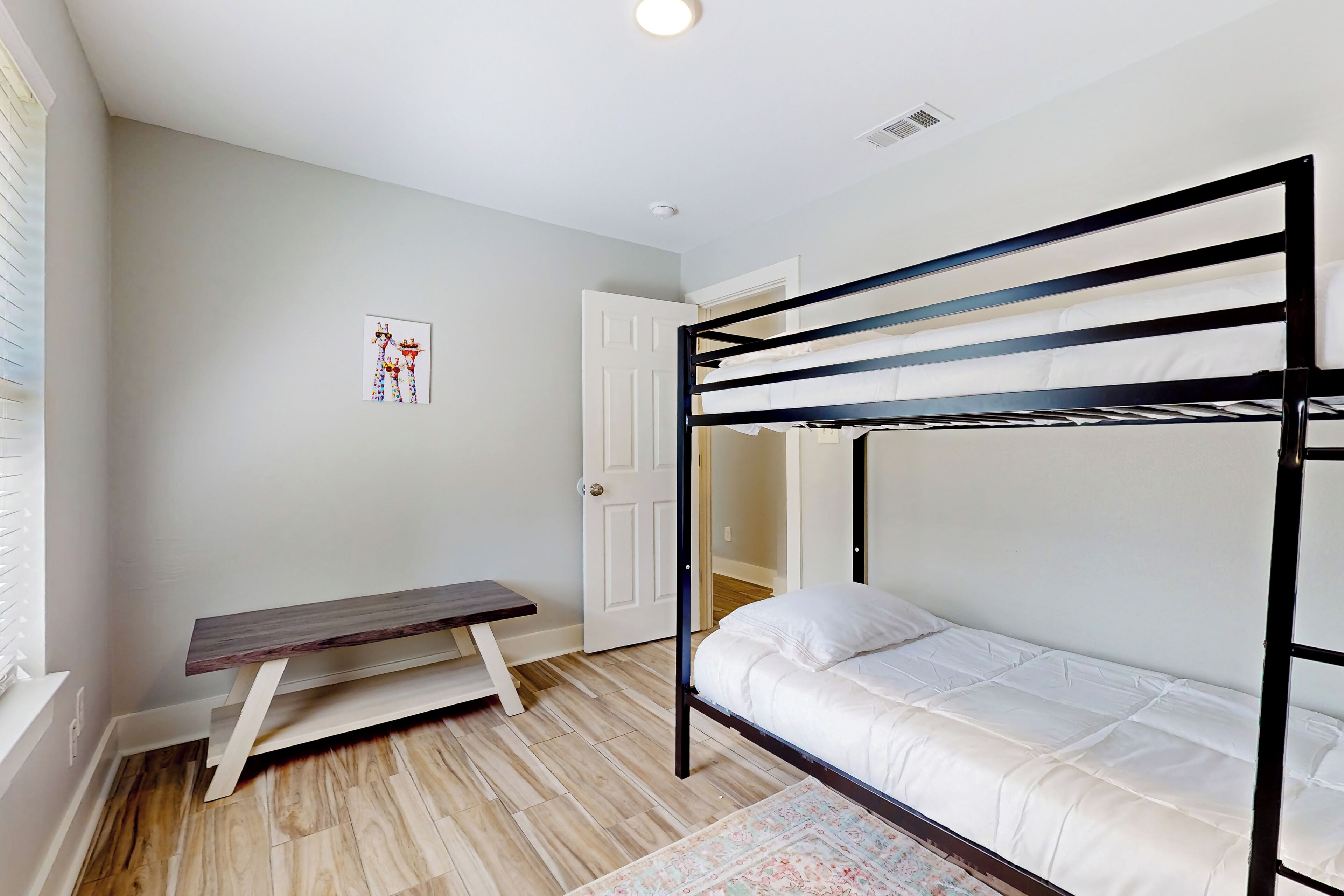 Een slaapkamer met een stapelbed, een houten bank en een deur.