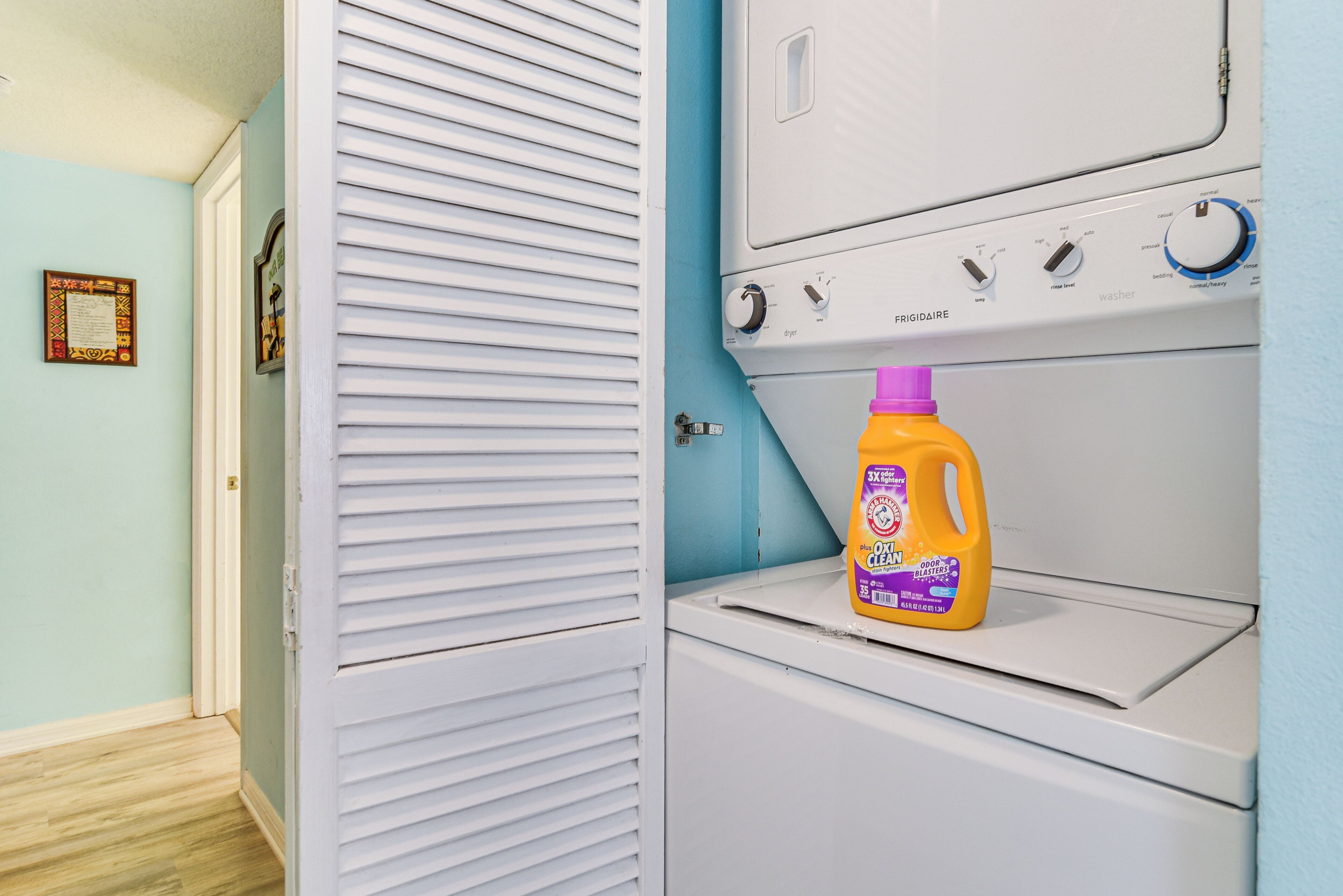 A laundry area with a washing machine and a bottle of detergent.