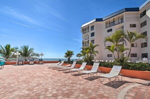 Cortile di un hotel con posti a sedere all'aperto, palme e vista sull'oceano.