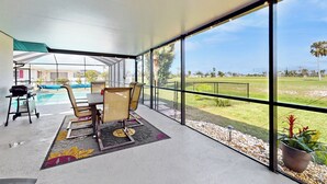 Varanda espaçosa com vista para uma piscina e um jardim bem cuidado.