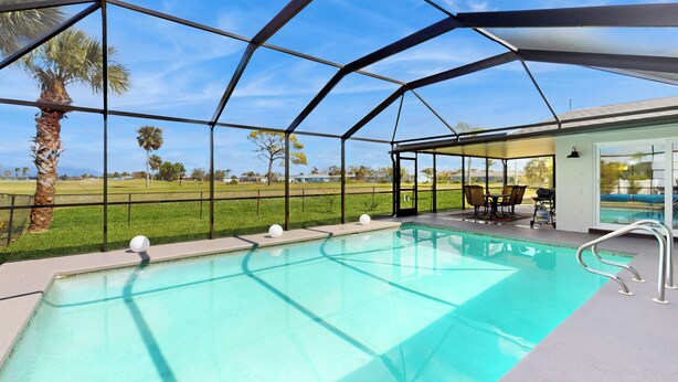 Piscina coberta com vista para a paisagem ao redor, incluindo palmeiras e uma área gramada.