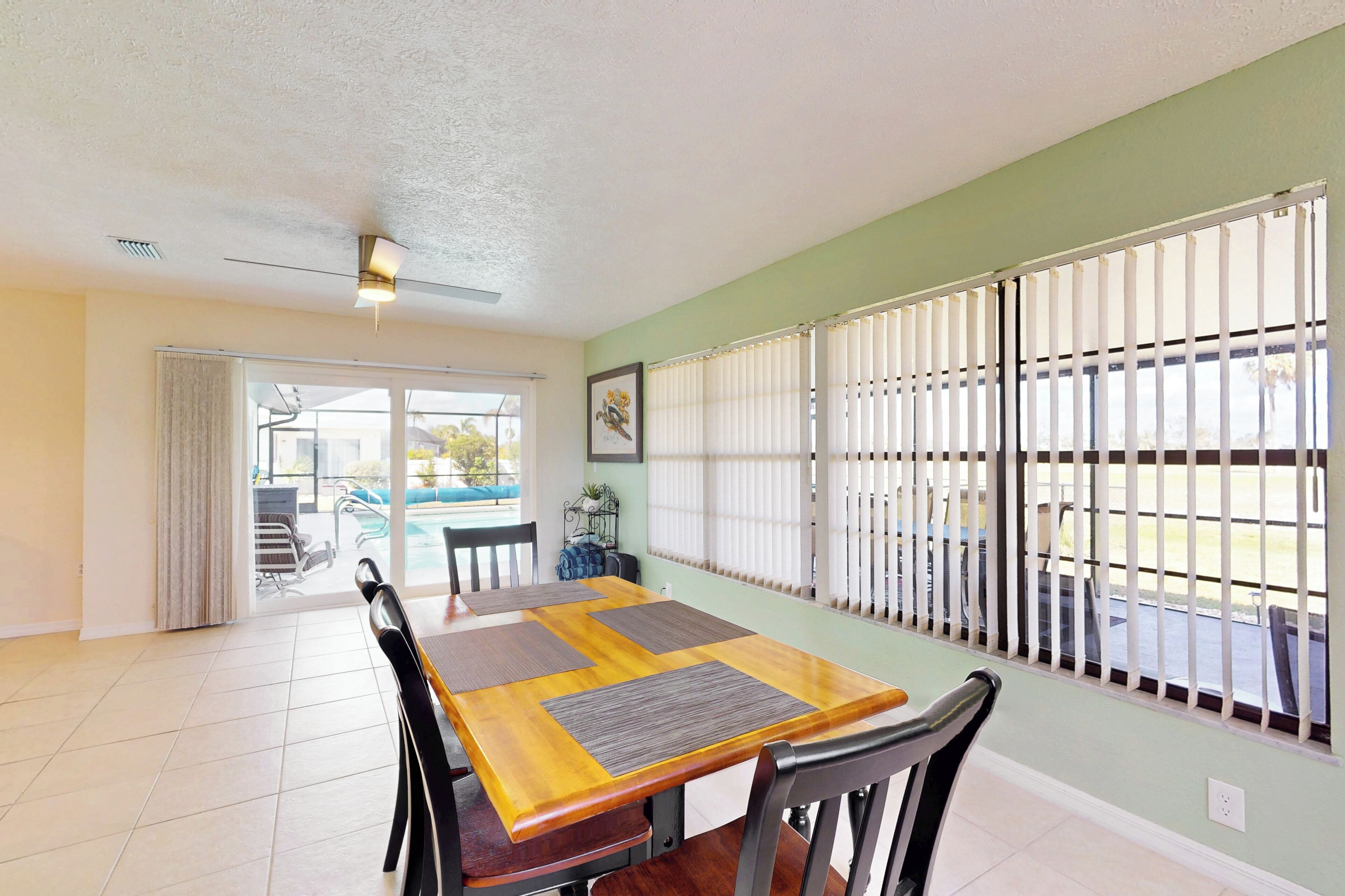 A dining area with a large table, chairs, and a view through a window with blinds.