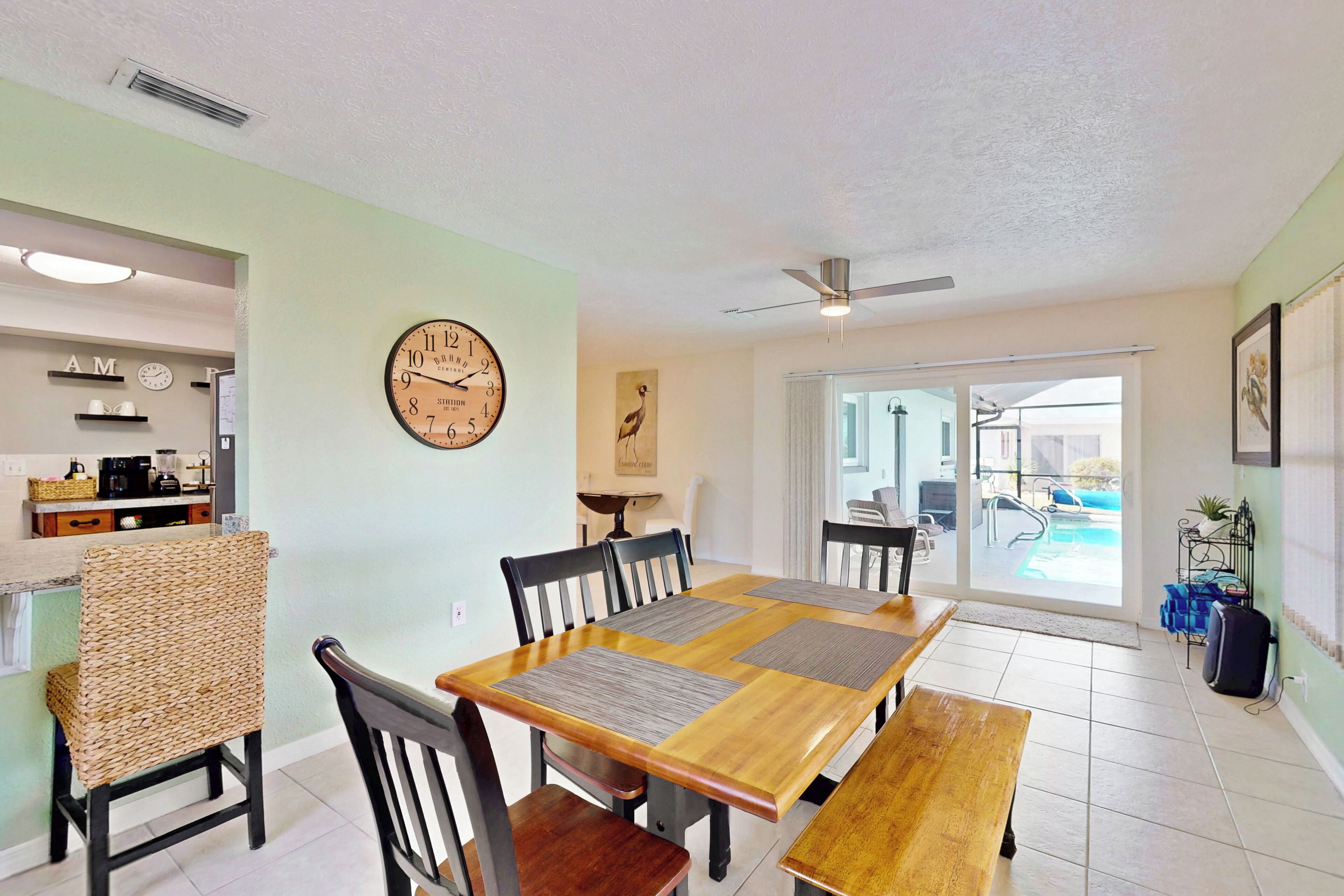 A dining area with a wooden table, chairs, and a clock on the wall.
