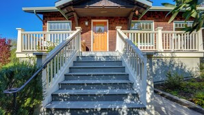 Ein zweigeschossiges Haus mit Holzfassade, einer Veranda und einer Treppe zum Eingang.