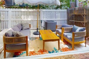 Un patio al aire libre con mobiliario de mimbre, una mesa y un paraguas decorativo.