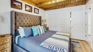 A bedroom with a large bed, wooden ceiling beams, and white doors. - Lake Tahoe Adventure Base! Townhome w/ Pool Access (Kings Beach)