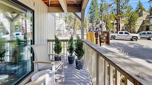 A wooden deck with a bench and potted plants, overlooking a street with parked vehicles and residential buildings. - Lake Tahoe Adventure Base! Townhome w/ Pool Access (Kings Beach)
