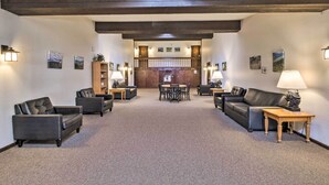 A spacious lobby with a high ceiling, dark wooden beams, and a carpeted floor. There are several black leather sofas and a wooden table with a lamp. - Woodsy Winter Park Condo w/ Pool & Hot Tub Access (Winter Park)